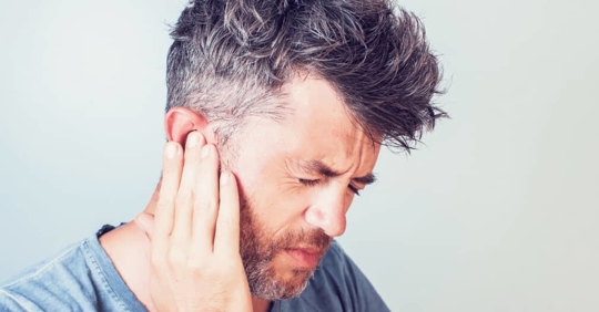 a man holding his ear in pain